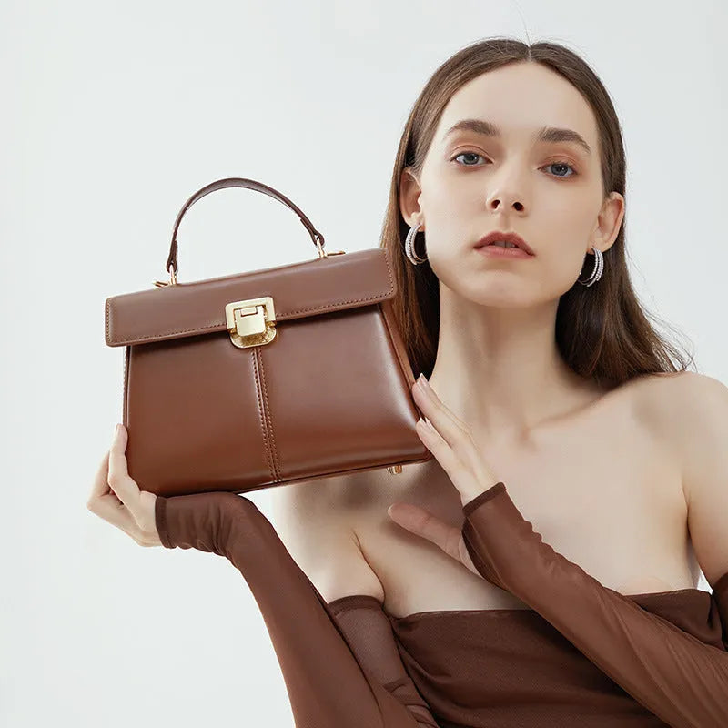 Black genuine vachette leather women's shoulder bag with clasp closure, showing square shape and adjustable strap.