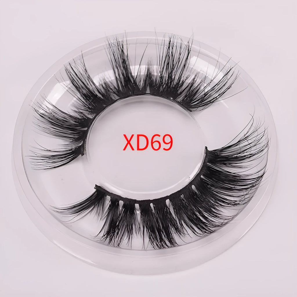 A pair of 5D style false eyelashes made from mink hair, shown with a double-headed brush and a black hair cap.