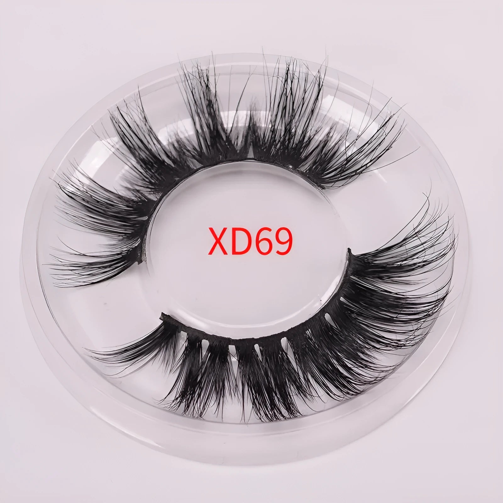 A pair of 5D style false eyelashes made from mink hair, shown with a double-headed brush and a black hair cap.