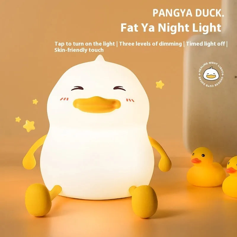 Chubby silicone pat night light on a desk holding a mobile phone, showing its compact size and soft design.