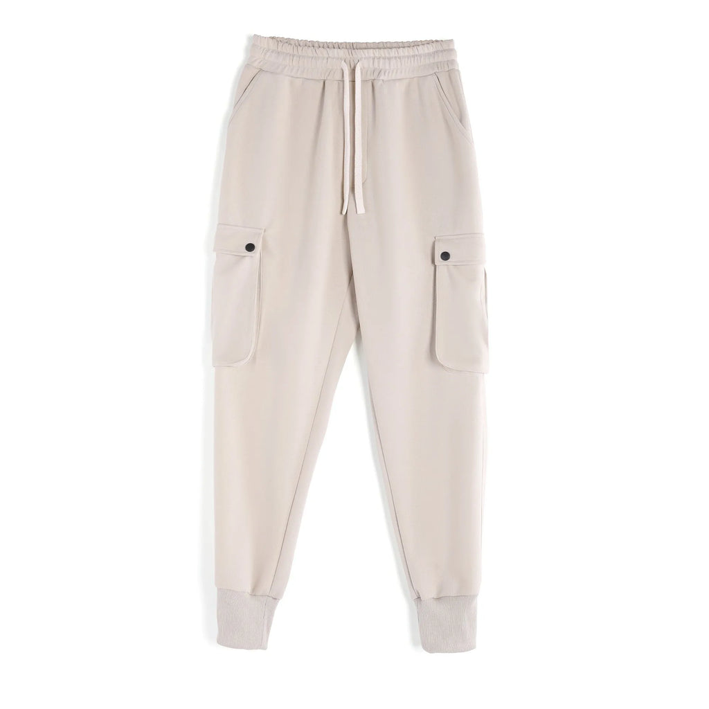 Man wearing loose light grey cotton trousers with ankle tie and multiple pockets, style of American sports leisure wear.