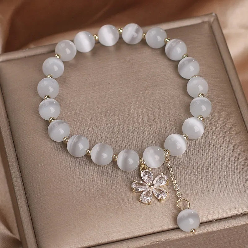 Women's single loop white cat's eye crystal bracelet with flower tassel and morganite safety buckle pendant.