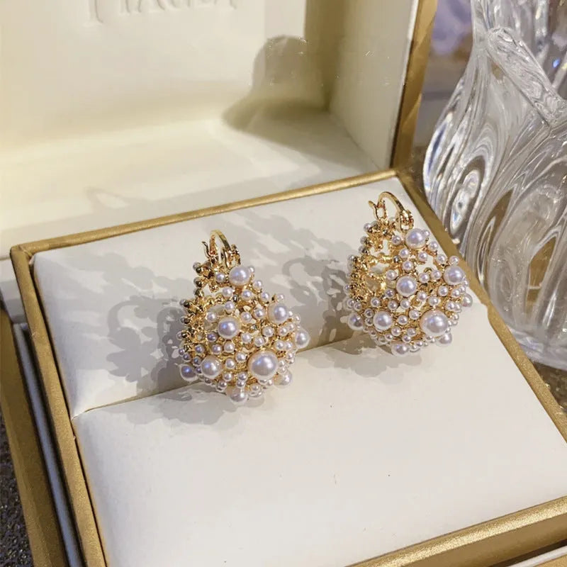 Gold-coloured copper flower basket earrings with small rice-shaped bead inlay detail.