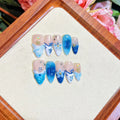 Set of blue carved plastic wearable artificial nails showing hand-painted summer ice design, laid out in sizes XS, S, M, L