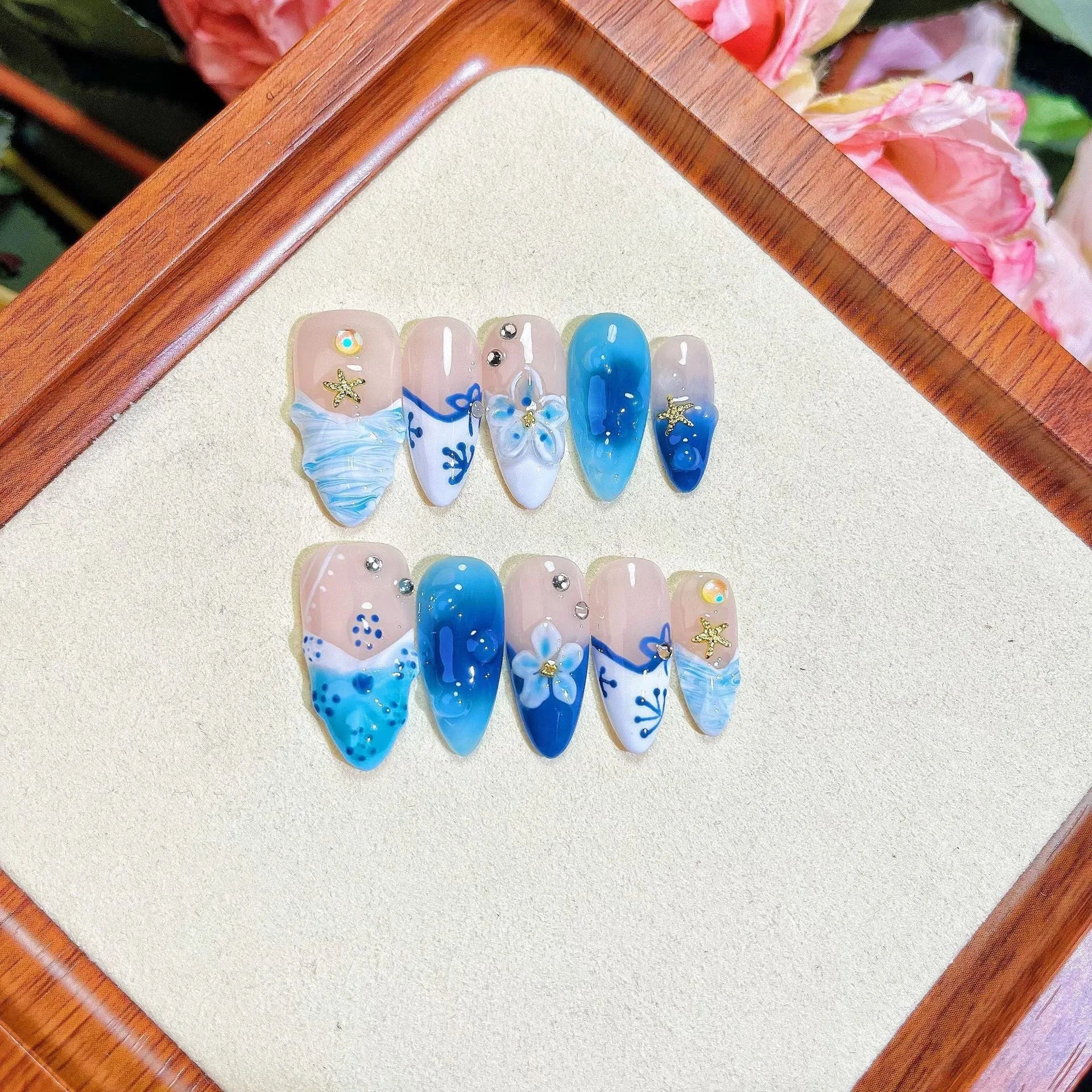 Set of blue carved plastic wearable artificial nails showing hand-painted summer ice design, laid out in sizes XS, S, M, L