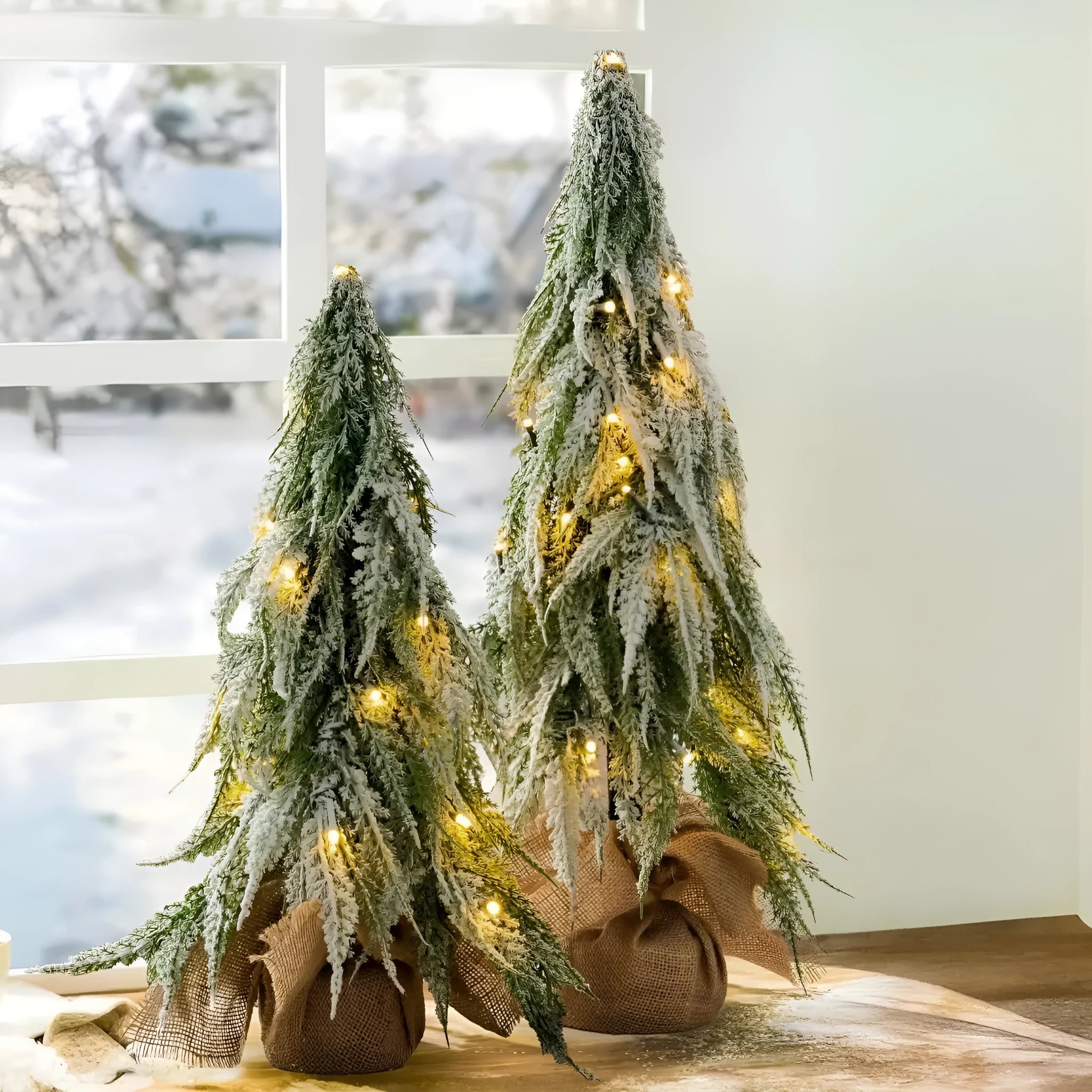 Small white artificial Christmas tree with snowy textured branches and built-in lights on a desktop