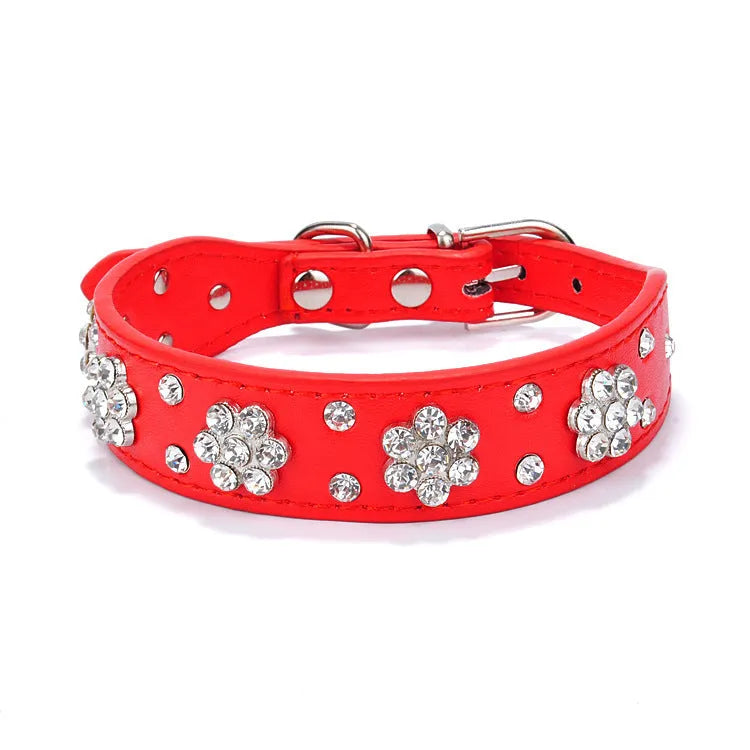 Close-up of a pink PU leather dog collar with silver rhinestone flowers and studs, showing the metal D-ring.