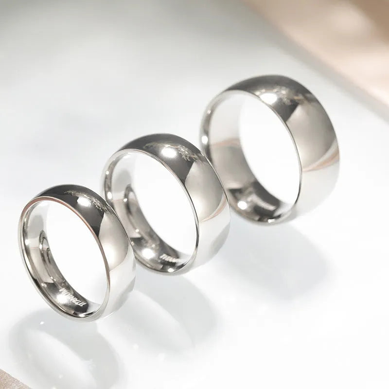 Silver titanium steel band ring shown in three widths: slim 2mm, standard 4mm, and wide 6mm on a plain background.