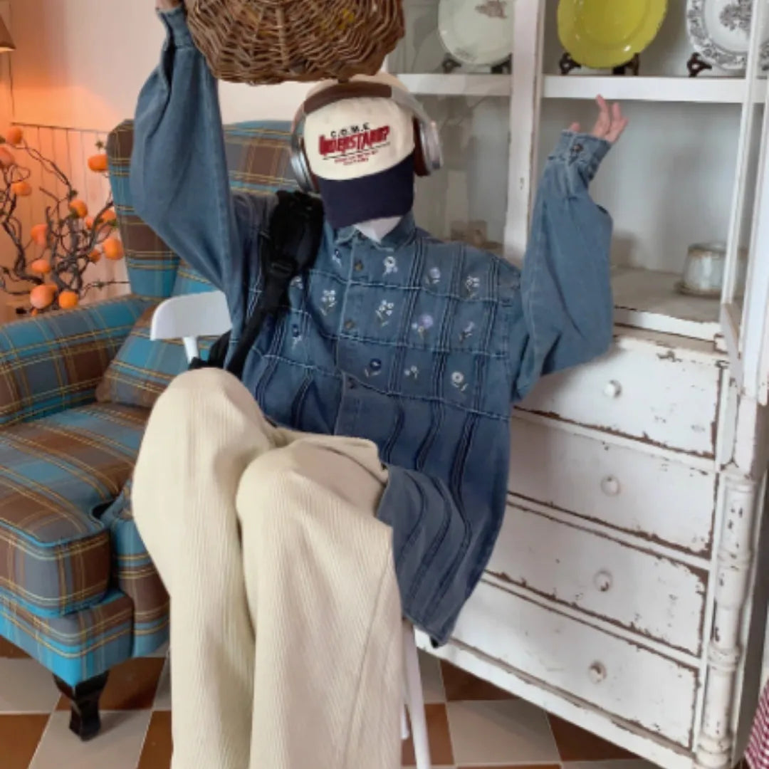 Washed blue denim long sleeve shirt with small floral pleated details on front.