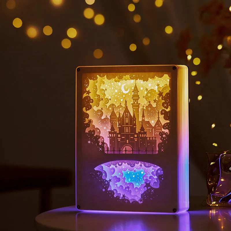 Modern bedside USB night light with paper carving design and remote control on a table.