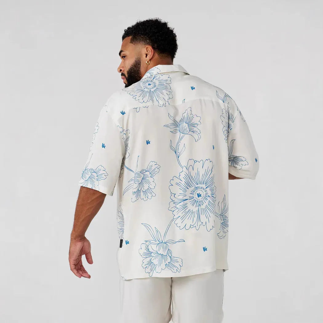 Man wearing a loose grey short sleeve cardigan top with a white floral print pattern.