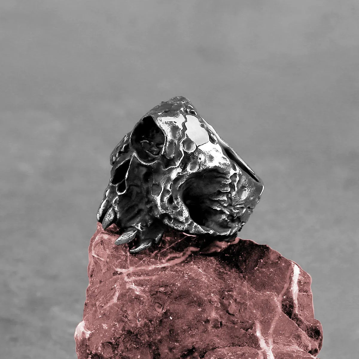 Close-up of a silver-toned alloy ring with a detailed one-eyed skull design on the finger.