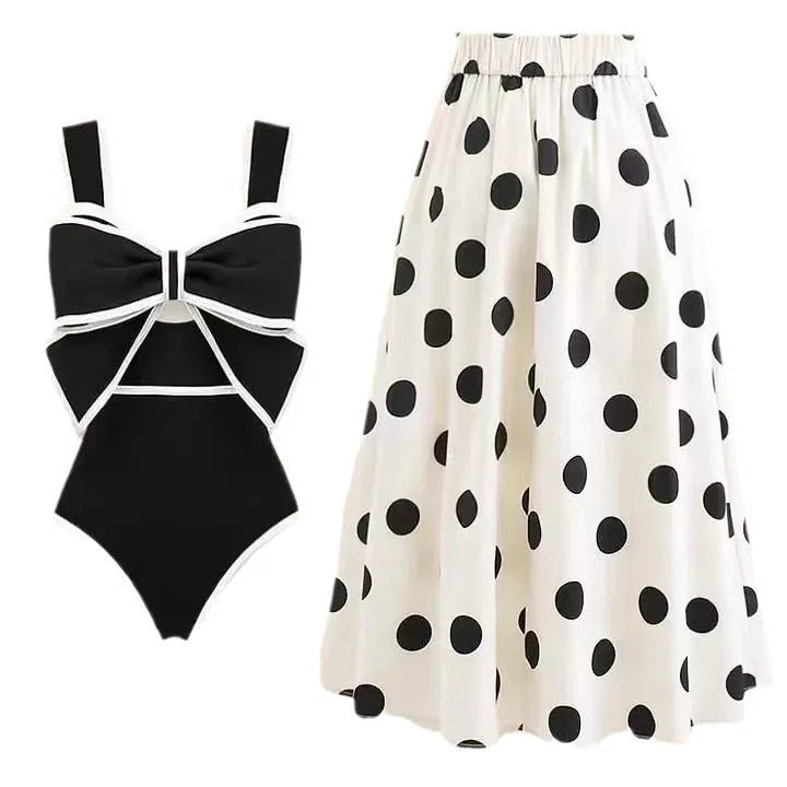 Women's black one-piece swimsuit with a white bow-accented beach dress cover-up skirt.