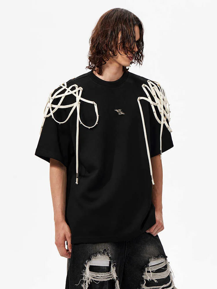 Black loose fit short sleeve T-shirt with ribbon and rivet decorated padded shoulders.