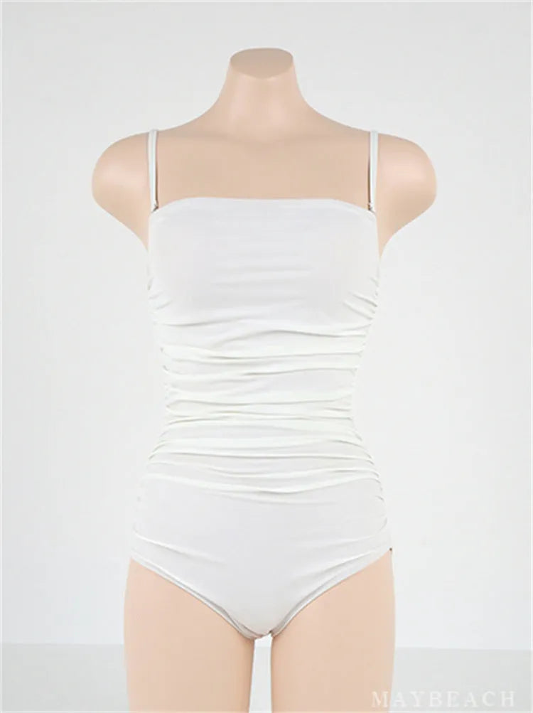 Sling style one-piece swimsuit with belly pleating in a solid colour.
