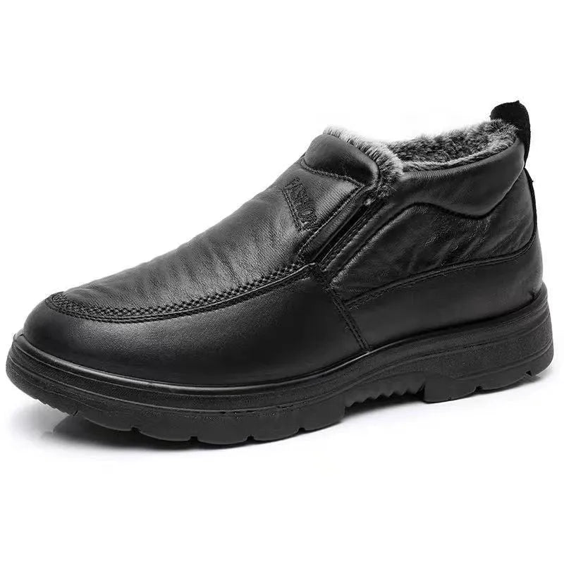 Men's black and brown fleece-lined winter slip-on shoes with rubber soles on a wooden floor.