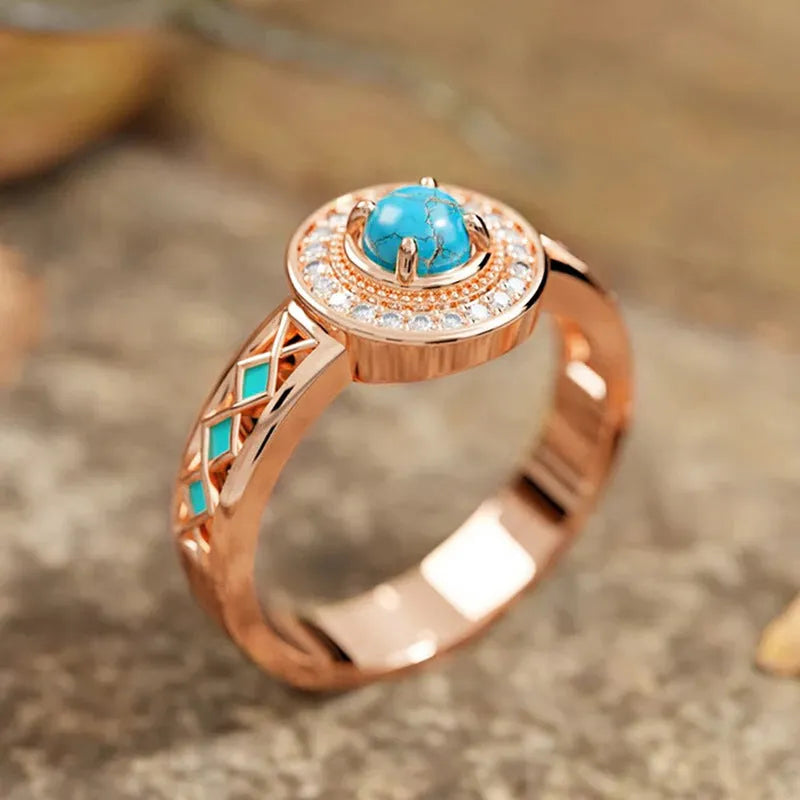 Close-up of a women's rose gold turquoise ring with geometric inlaid zircon stones on a copper band.