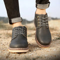 Men's black mid-top British leather boots with flat rubber sole on a neutral background