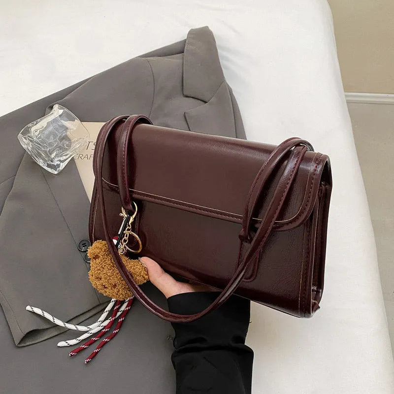 Brown women's structured square PU leather shoulder bag with a detachable tassel pendant and double straps.