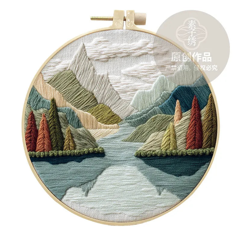 DIY landscape embroidery kit with cotton fabric, bamboo frame, threads and needles arranged for crafting