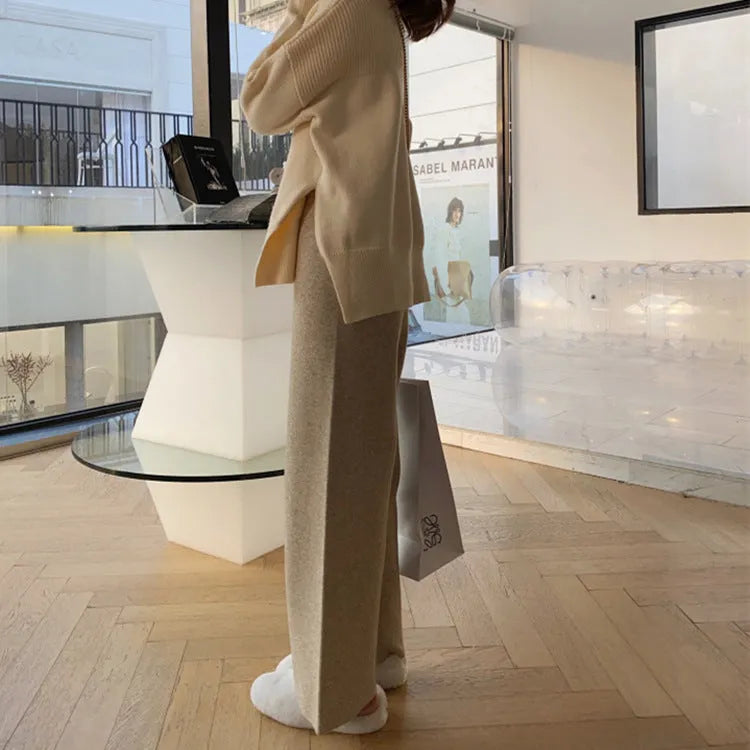 Woman wearing high waist cream white knitted wide-leg trousers with a straight, drooping mopping cut.