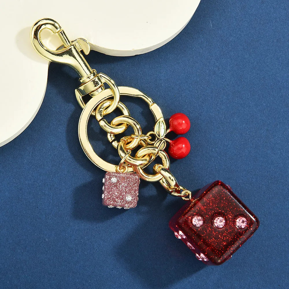 Square metal keychain pendant with a vintage two-tone cherry dice pattern on a white background.