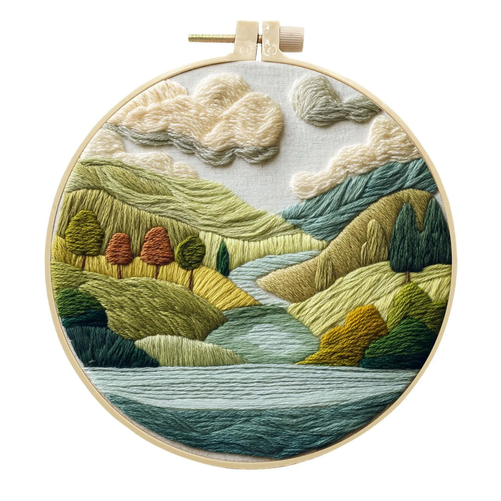 DIY landscape embroidery kit with cotton fabric, bamboo frame, threads and needles arranged for crafting