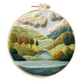 DIY landscape embroidery kit with cotton fabric, bamboo frame, threads and needles arranged for crafting