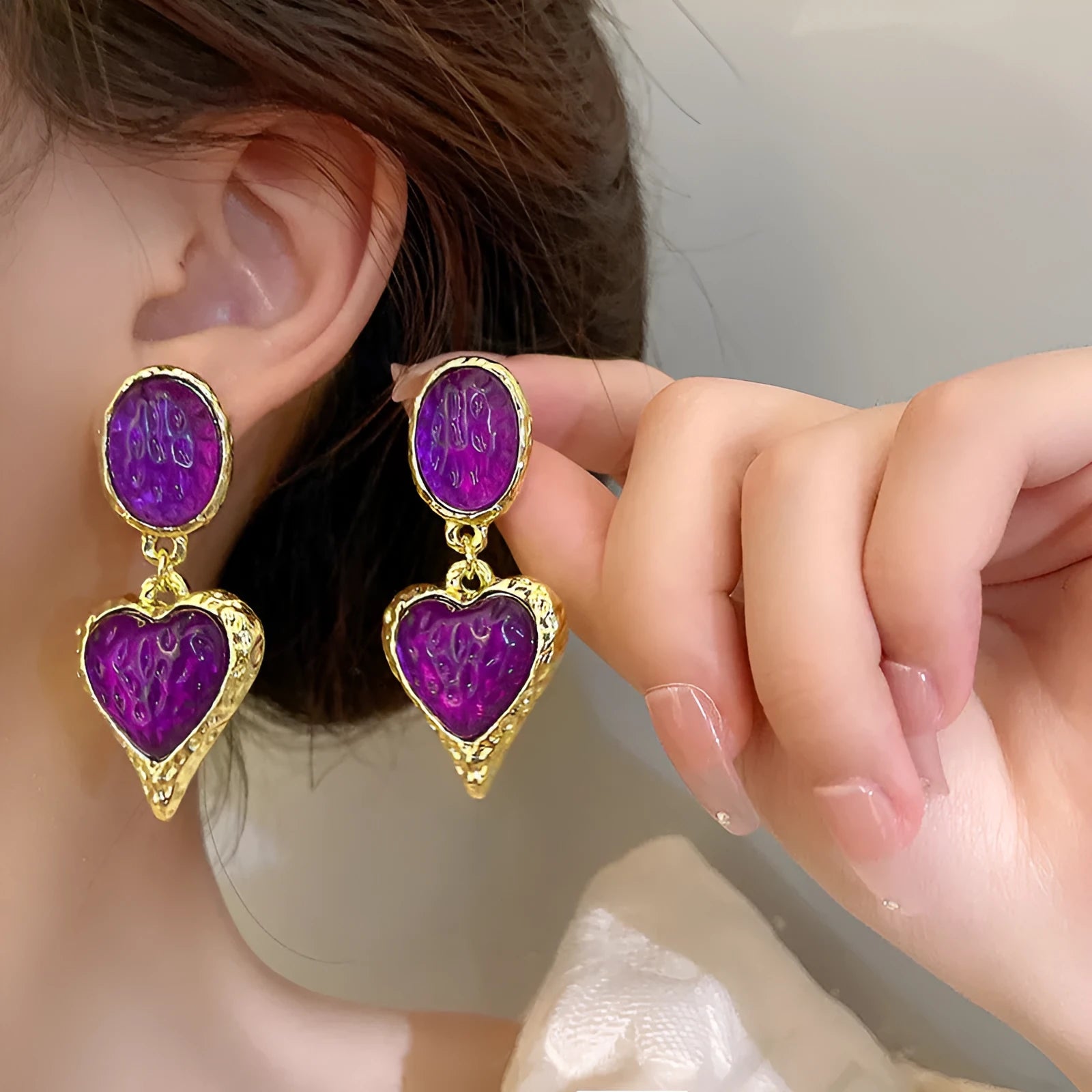 Oval-shaped love heart stud earrings with a pleated silver texture in purple, red, green, and yellow/white colours.