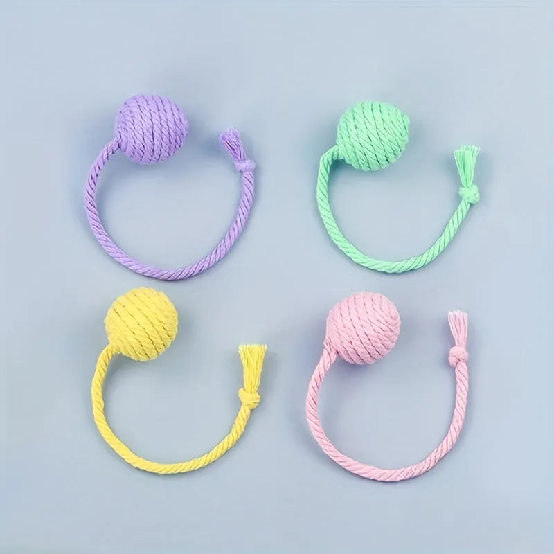 Coloured cat toy ball with rope attached and built-in bell inside, shown in green, pink, purple, and yellow options