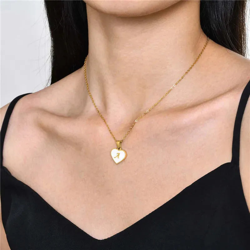 Gold-plated heart necklace with white shell pendant personalised with a letter, on an adjustable chain.