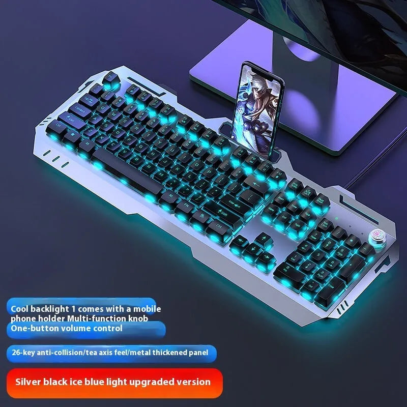 Aluminium gaming keyboard with volume knob, shown in metal grey with RGB lighting alongside optional macro mouse and headset.
