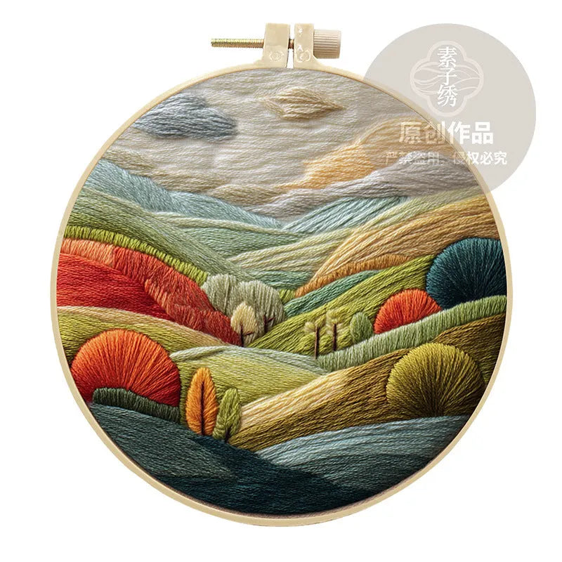 DIY landscape embroidery kit with cotton fabric, bamboo frame, threads and needles arranged for crafting