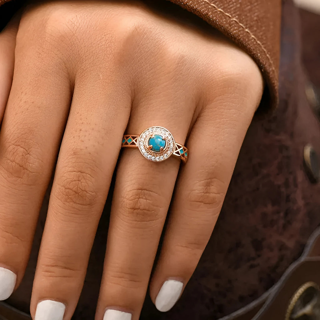 Close-up of a women's rose gold turquoise ring with geometric inlaid zircon stones on a copper band.