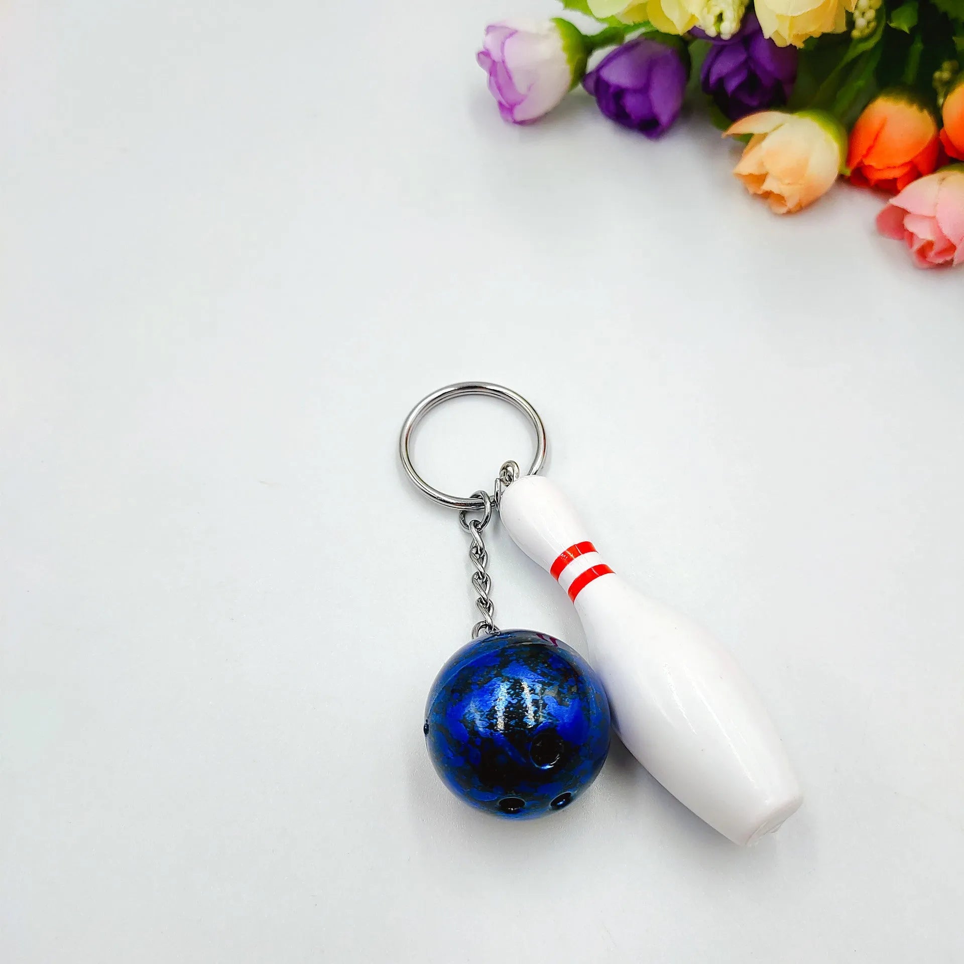 Mini sports bowling keychain pendant in PVC metal, shown in dark red, blue, purple, and green colour options.